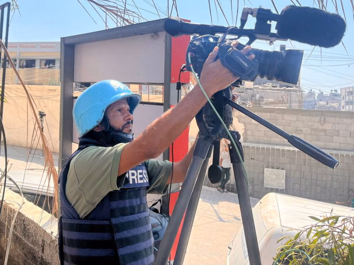 Masri mengatur kameranya saat merekam sebuah adegan di Khan Younis pada 7 Agustus. REUTERS/Stringer