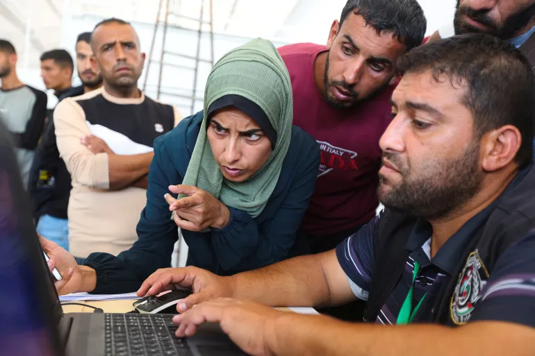 Seorang wanita Palestina menatap layar komputer, berusaha mengenali suaminya yang hilang di antara foto-foto jenazah yang diserahkan oleh Israel (Reuters)