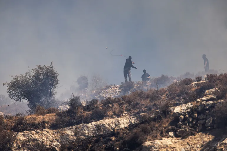 Gemini berkataPemukim bermasker melemparkan batu ke arah warga Palestina dari atas bukit di desa Sinjil, Tepi Barat yang diduduki (AFP - Arsip)