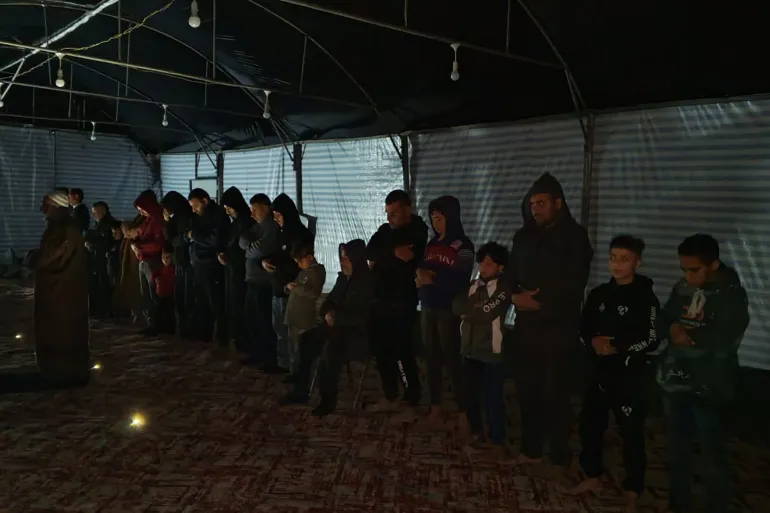 Para jemaah menunaikan salat mereka di masjid-masjid dari nilon dan besi tanpa penerangan dan di bawah bunyi peluru pihak pendudukan (Al Jazeera)